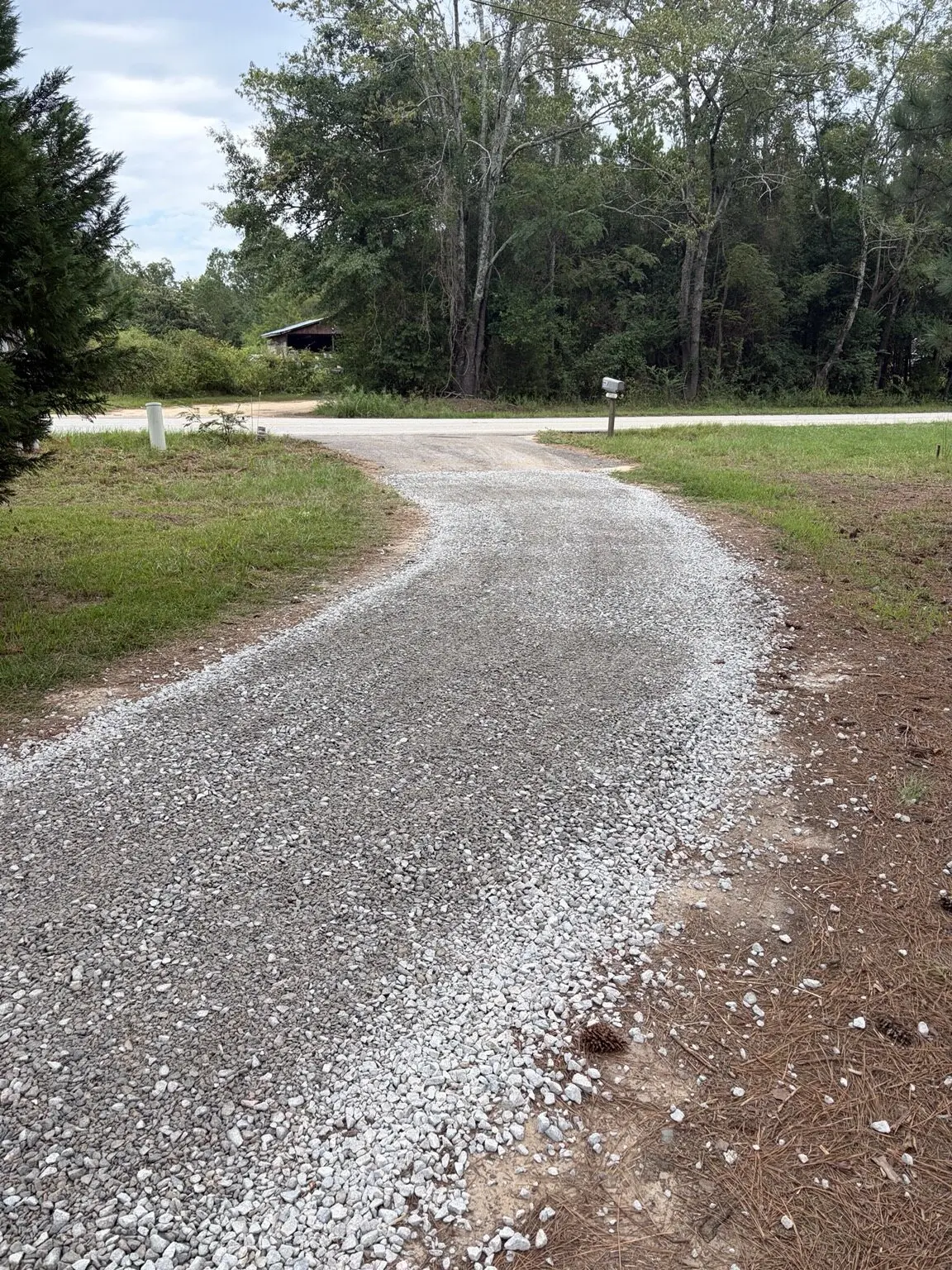 Gravel driveway spread by RSL, curving through the grass toward a tree line